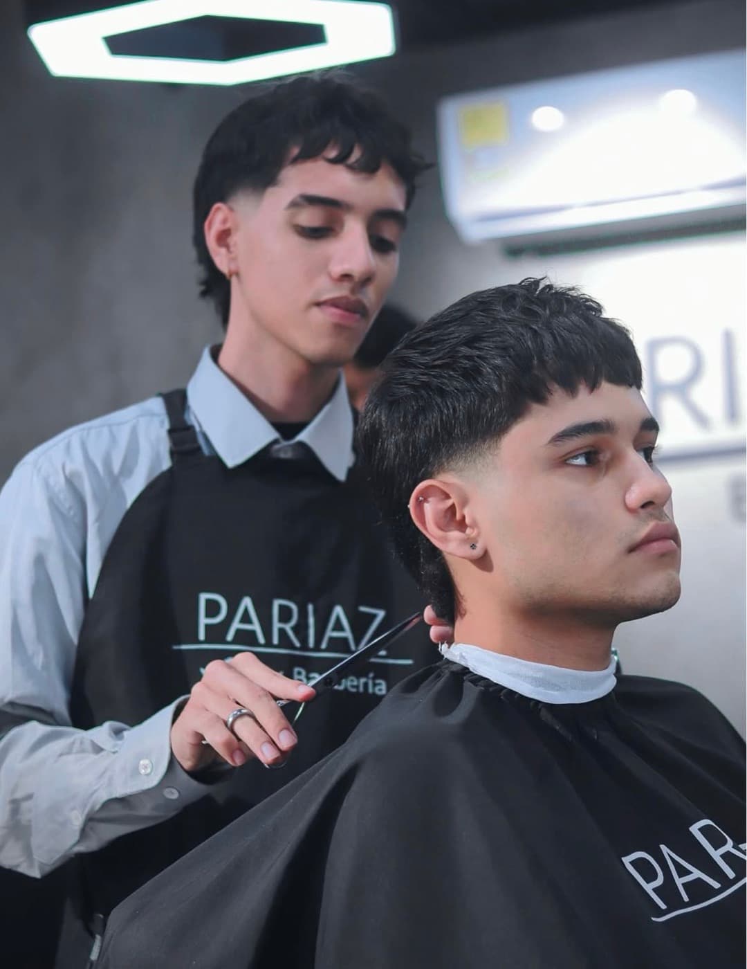 Barbero de Pariaz cortando el cabello a un cliente